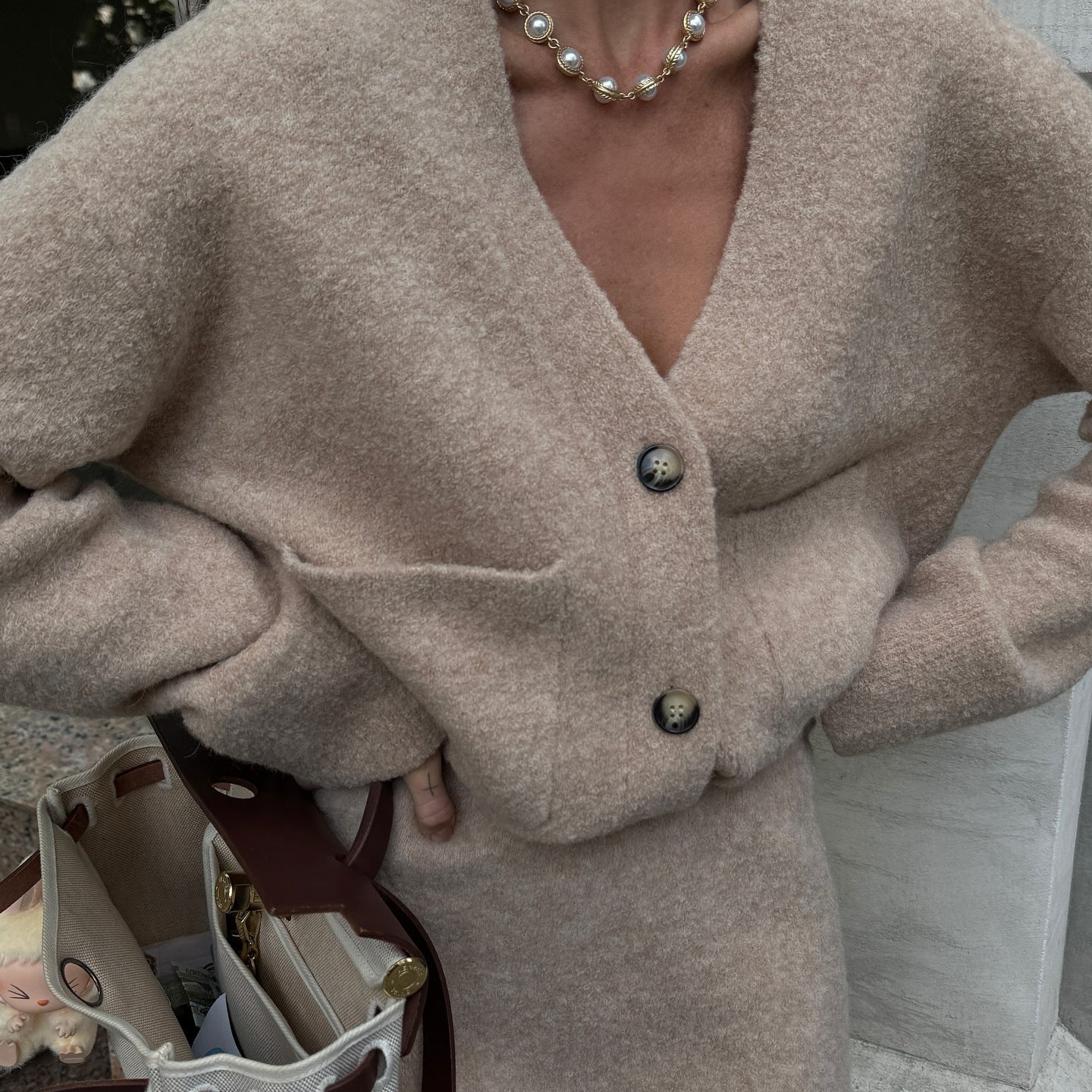 Conjunto de saia e blusa larga com decote em V e saia curta evasé de cintura média, em lã.